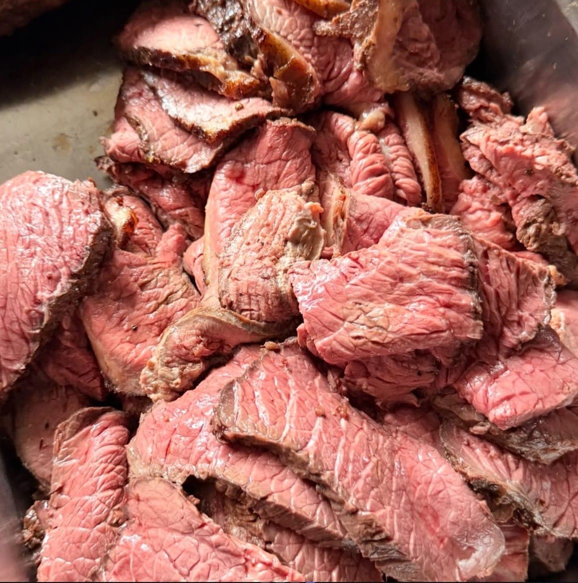 Roast beef carved into thick slices, pink in the middle with a browned crust.