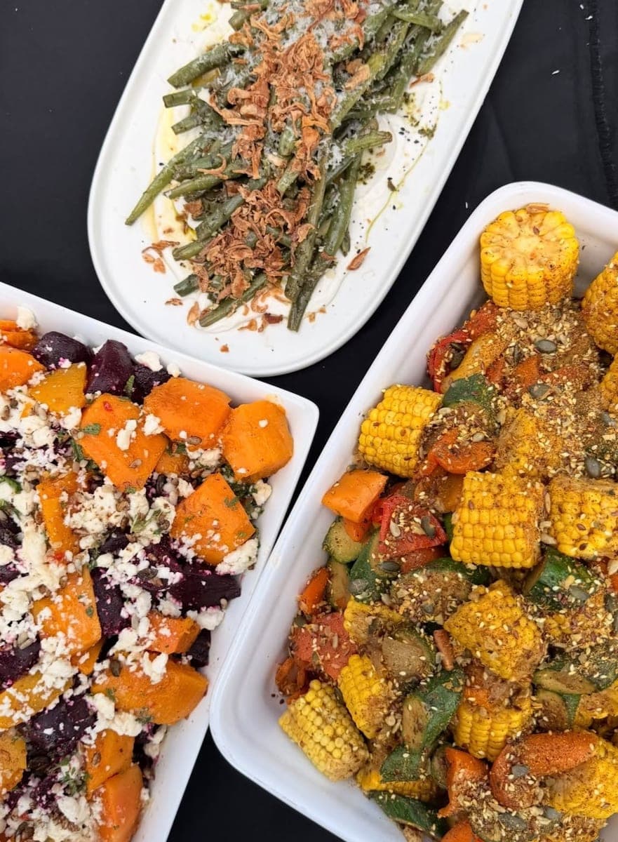 Three sides from above: green beans with crispy onions, roasted beetroot and pumpkin with crumbled feta, and roasted vegetables and corn under a seeded spice crust.