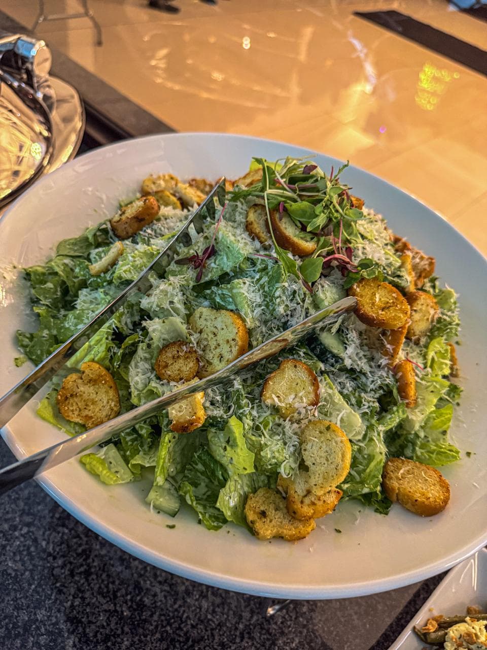 A Caesar salad with croutons and shaved parmesan.