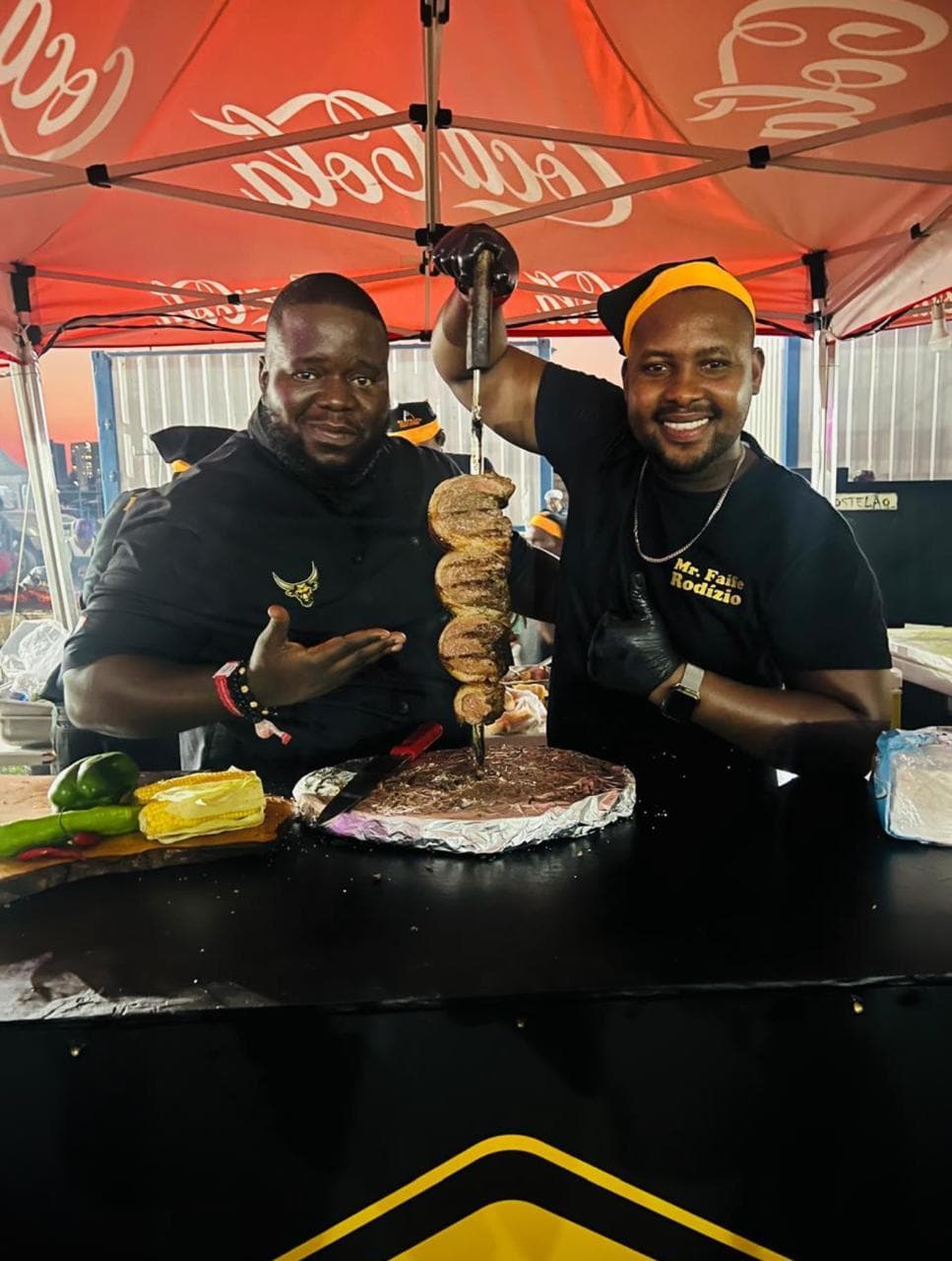 Biggy and a chef from Mr Faife Rodizio posing with a skewer of grilled meat fresh off the fire.
