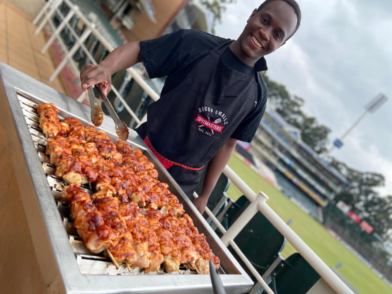 A crew member threading skewers onto the grill in a Biggy Smallz shirt.