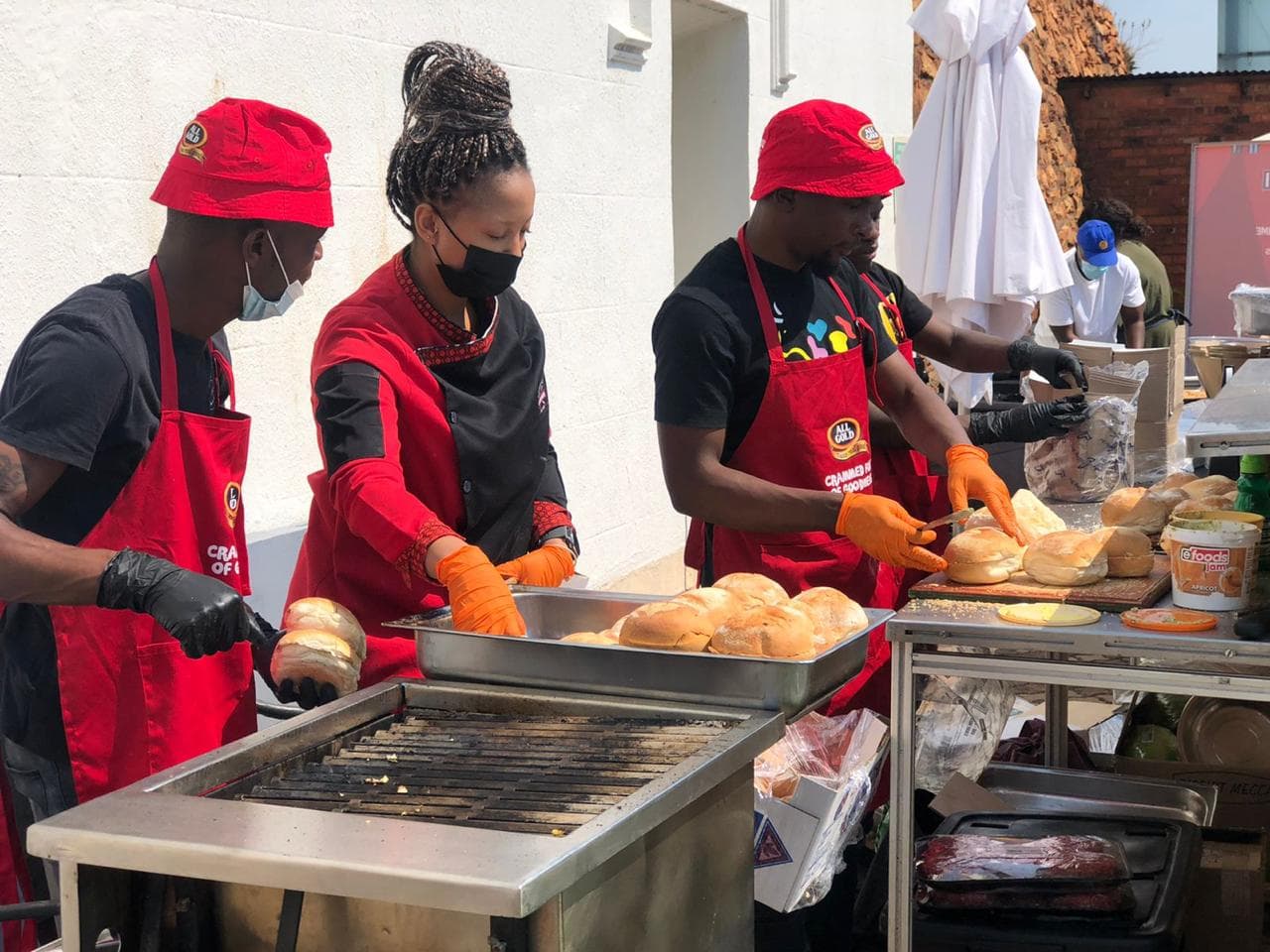 The crew grilling rolls together at the same outdoor sponsor event.