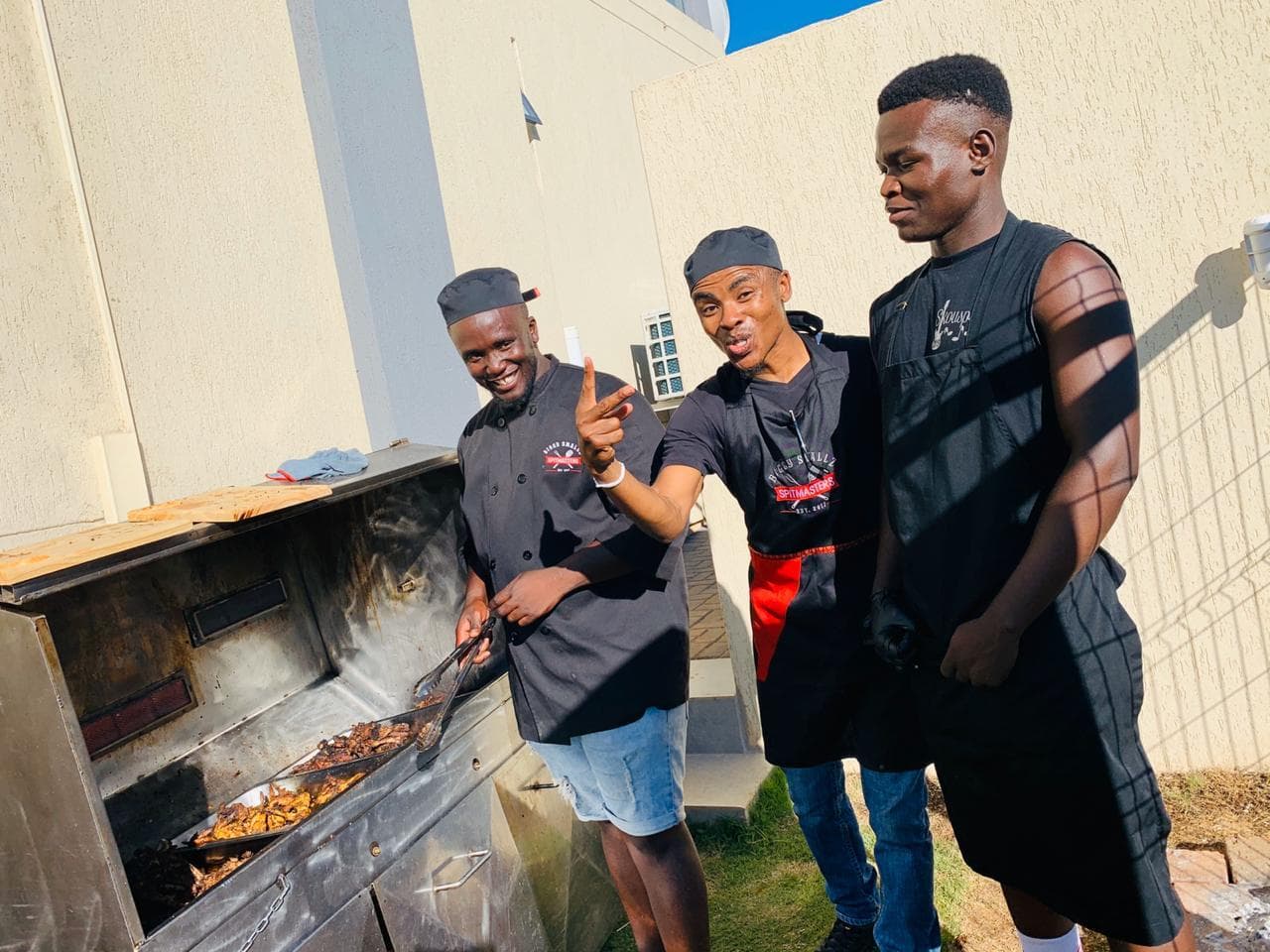 Three of the crew working the grill at a backyard braai.