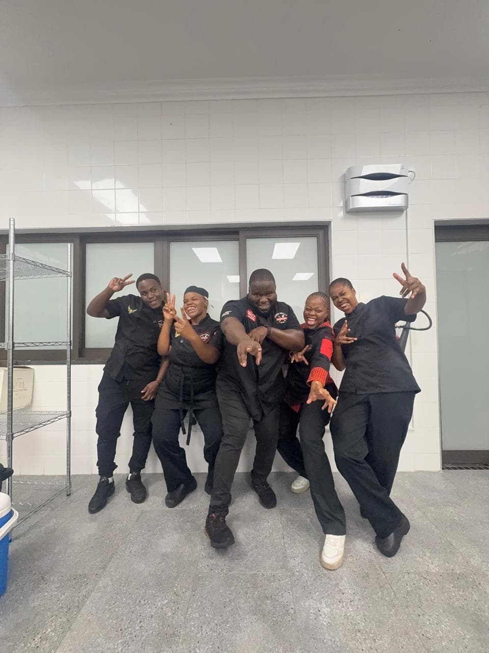 Five of the crew posing together in the back kitchen, in blacks.