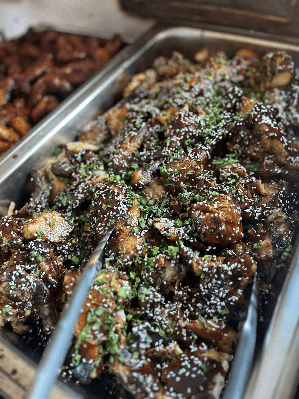 Glazed sesame-topped chicken in a tray.