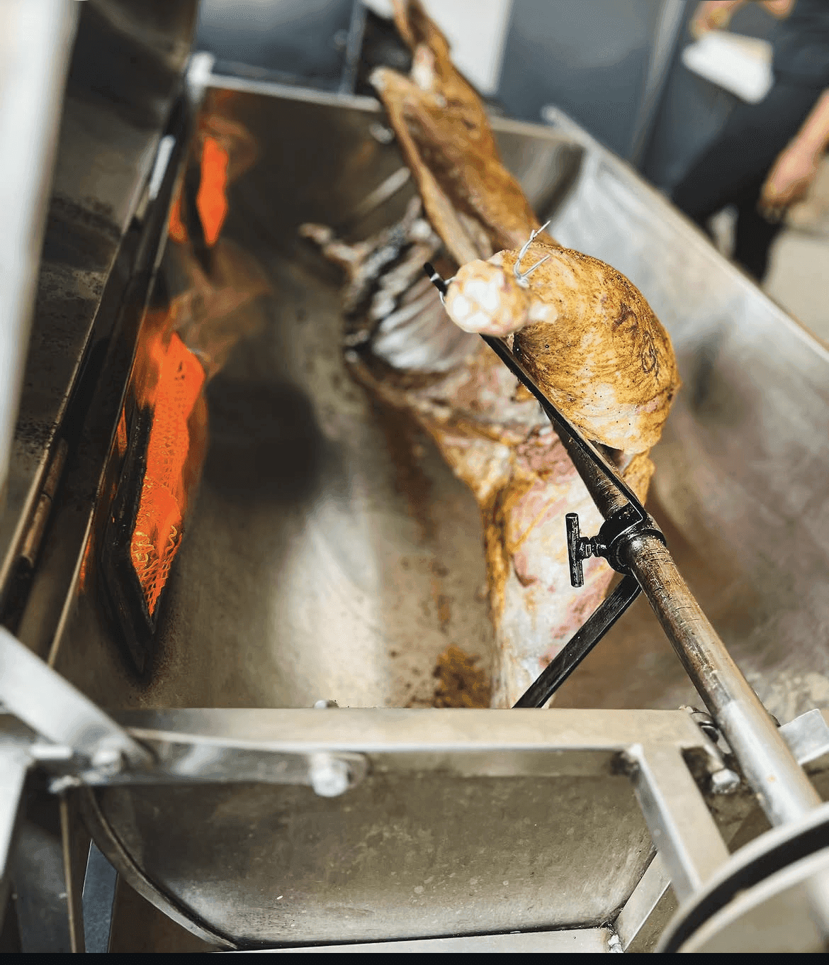 A whole lamb roasting on the spit with open flame.