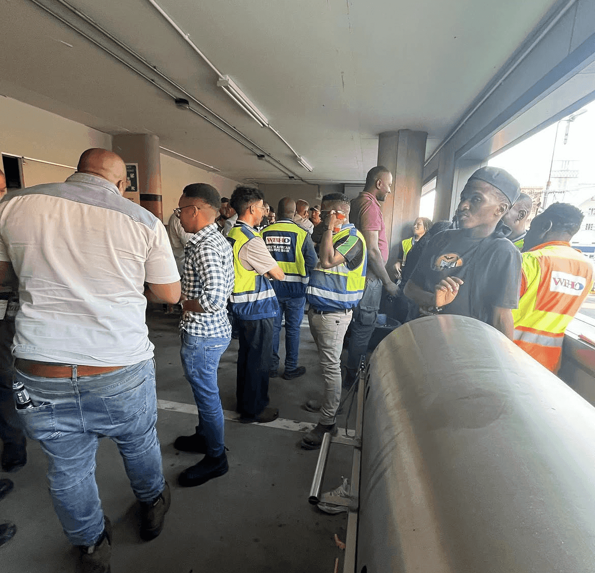 Site workers in WBHO hi-vis vests queuing for food.
