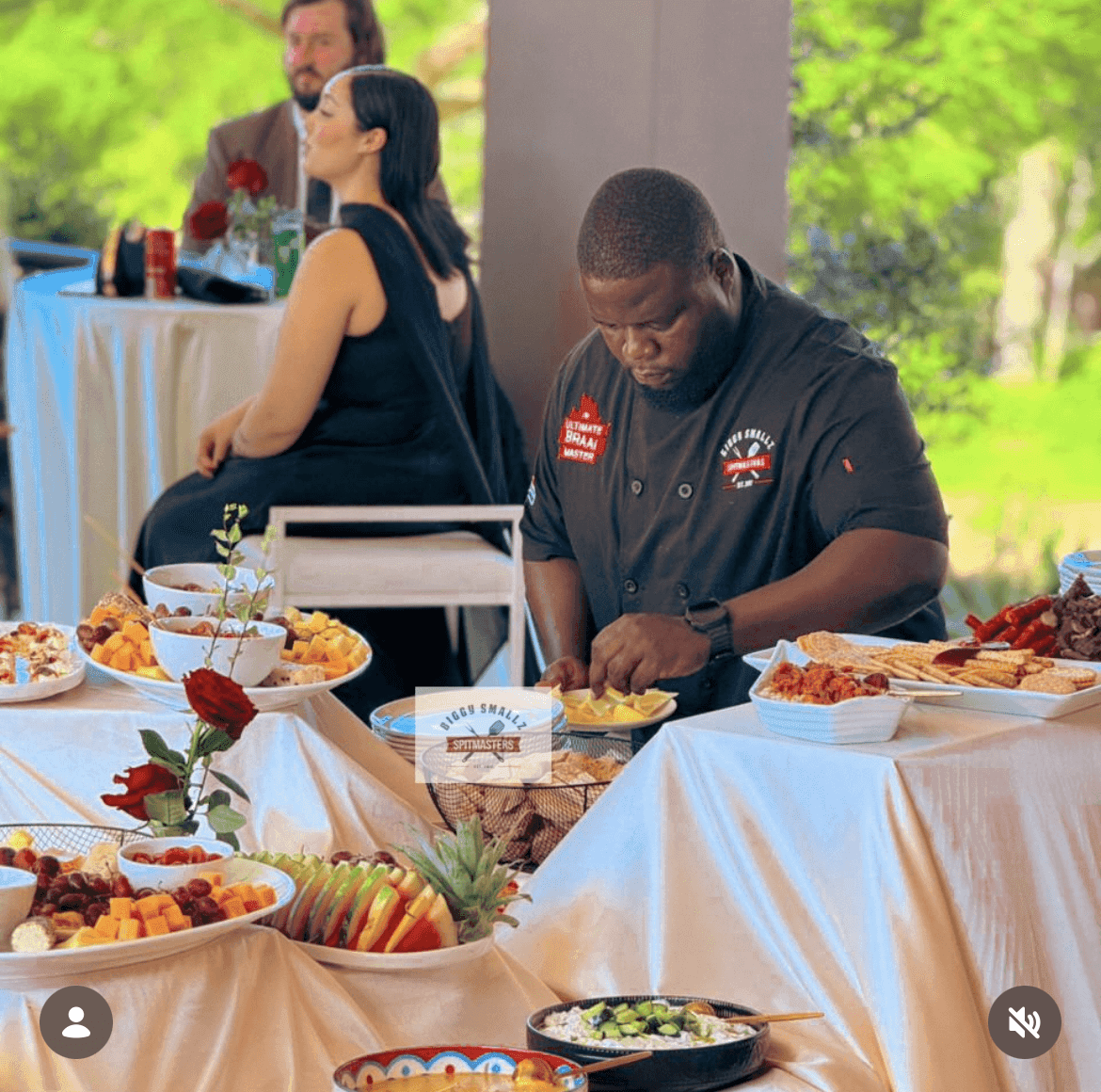Biggy plating at the harvest table while the couple sit alongside.